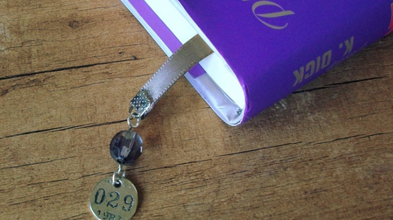 Ribbon bookmark with charm attached hanging from a purple book