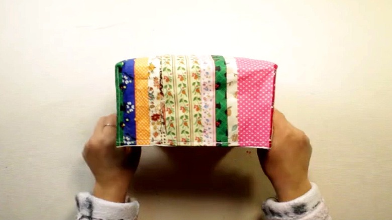 Person holding a storage box they decorated with scrap ribbon