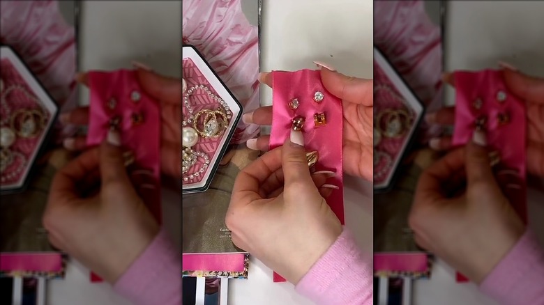 Person holding pink ribbon with earrings through it