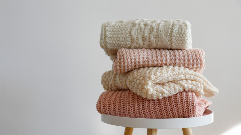 Folded sweaters on stool