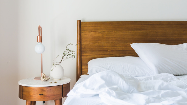 White and wooden nightstand and bed in bedroom