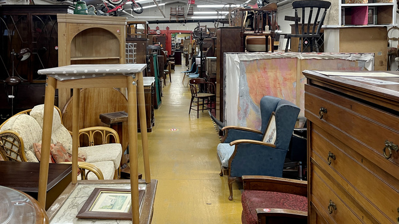 Furniture aisle in thrift store with many dated pieces