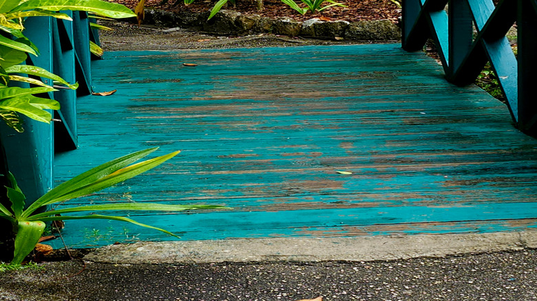 Brightly colored teal timber bridge in a forest setting