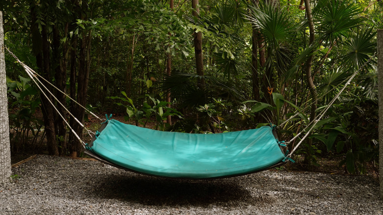 Teal-colored hammock hanging between two sturdy posts in a shaded backyard