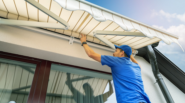 worker installing awning on home