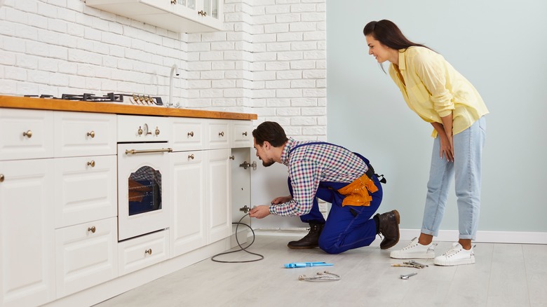 Homeowner and professional inspecting plumbing