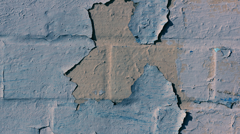 Flaking blue paint on brick