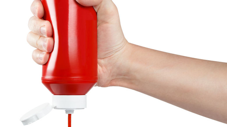 Hand squeezing ketchup from bottle