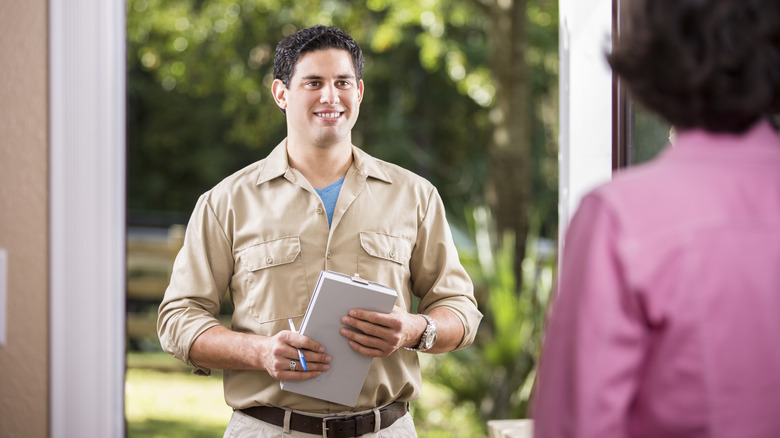 A pest control professional greeting a homeowner at their door