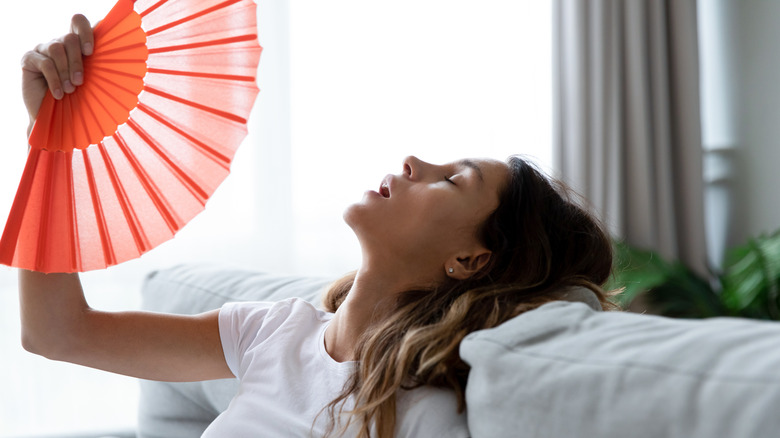 overheated woman waving paper fan