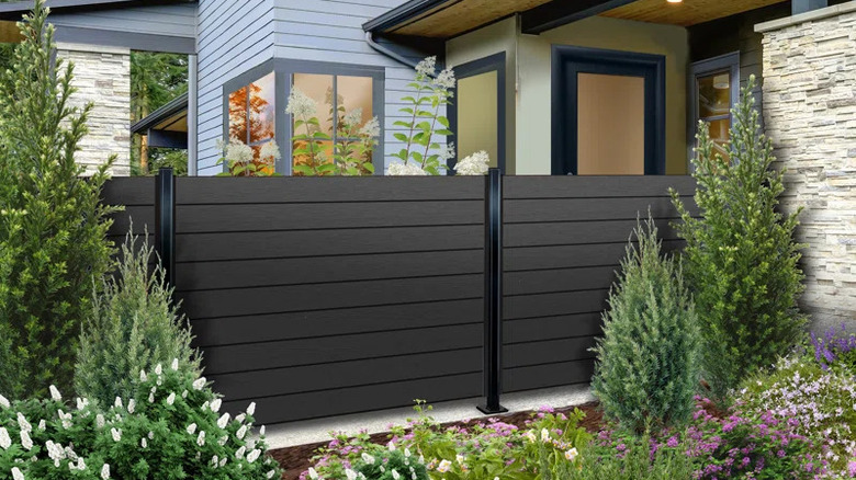 A composite wood fence between a house and a garden