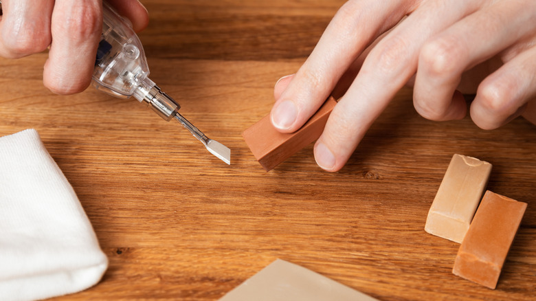 man heating hot wax to fix dent in wood