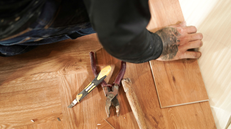 man replacing a single floor board