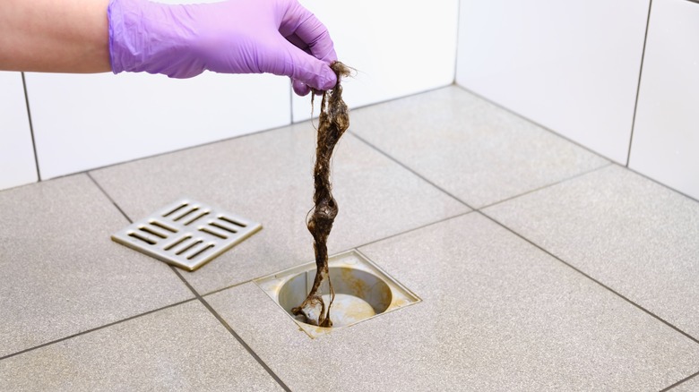 person removing hair from drain