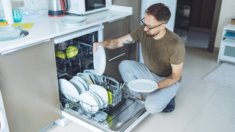 Man unloading dishes from dishwasher