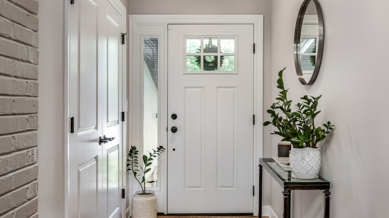 A home's entryway with a console, plants, and a mirror