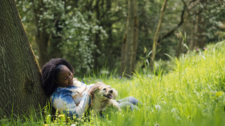 Young woman with dog leaning against tree