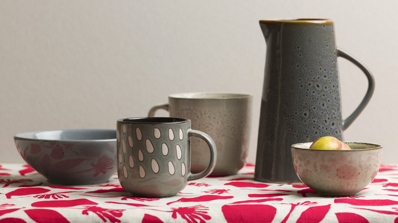 gray and blue ceramic dishes on red tablecloth