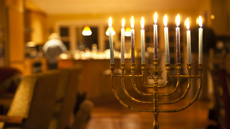 gold menorah lit with candles in home