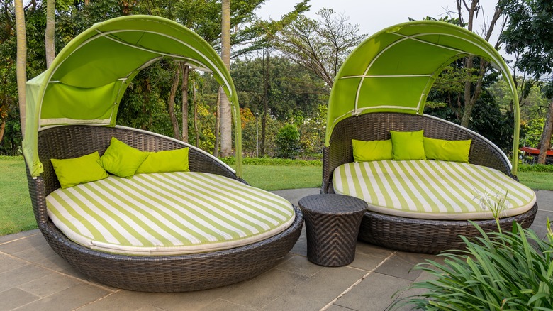 Two covered outdoor daybeds on a patio.