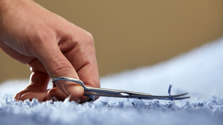 Man cutting carpet fibers