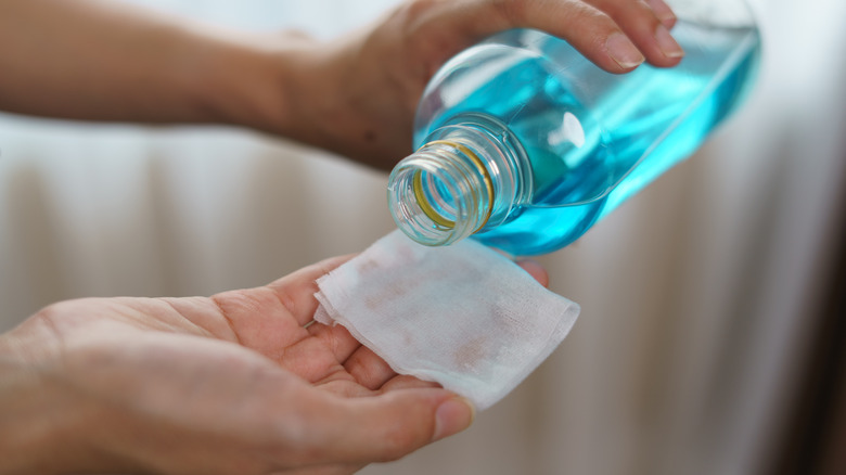 person pouring rubbing alcohol on cotton