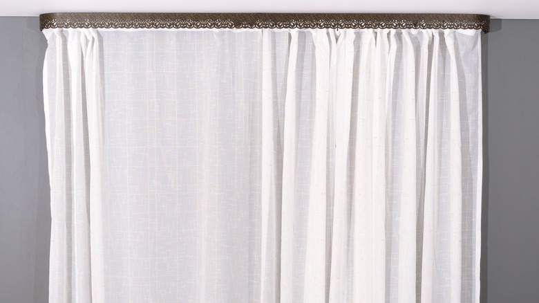 A white curtain hanging below a decorative piece