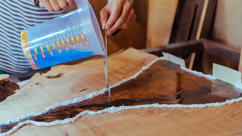 woman pouring epoxy resin on wood