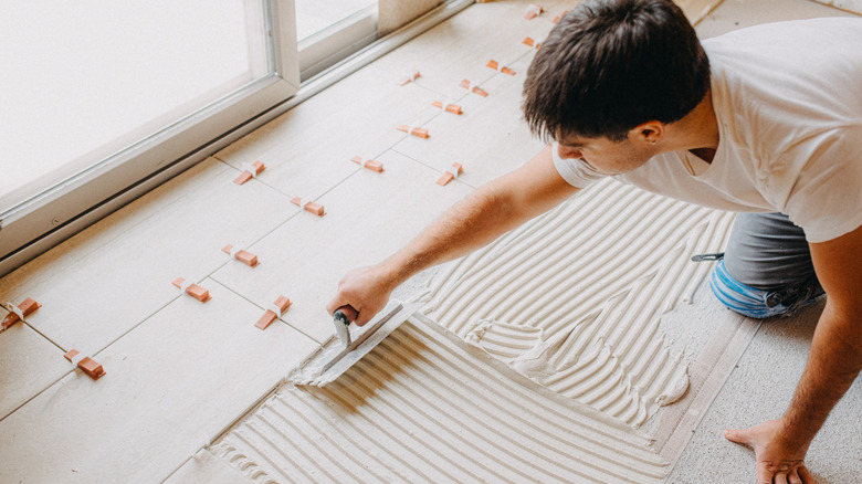 Man spreading thin set for laying floor tiles