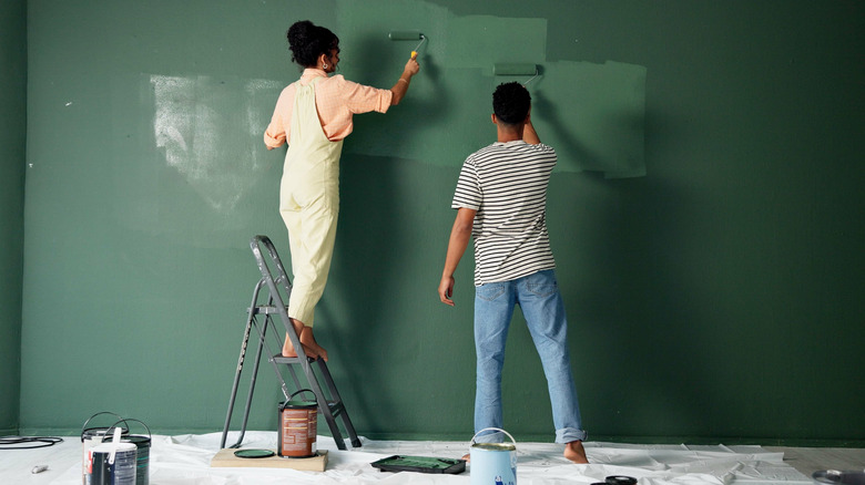 A man and a woman painting a wall a dramatic green