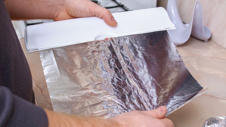 person tearing off aluminum foil