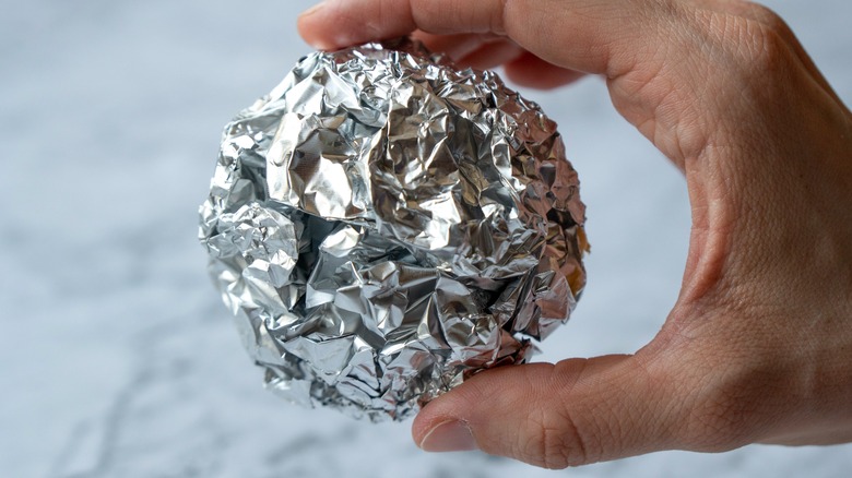 Hand holding aluminum foil ball