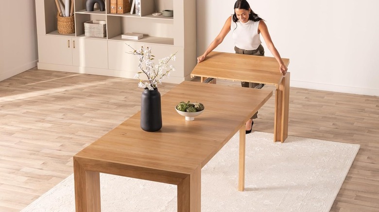 Woman extending 2-person dining table into a 12-person table