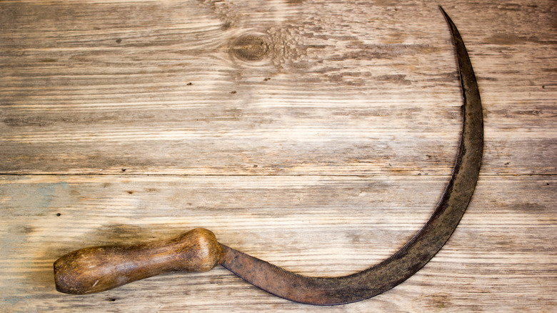 antique hand sickle garden tool on wood