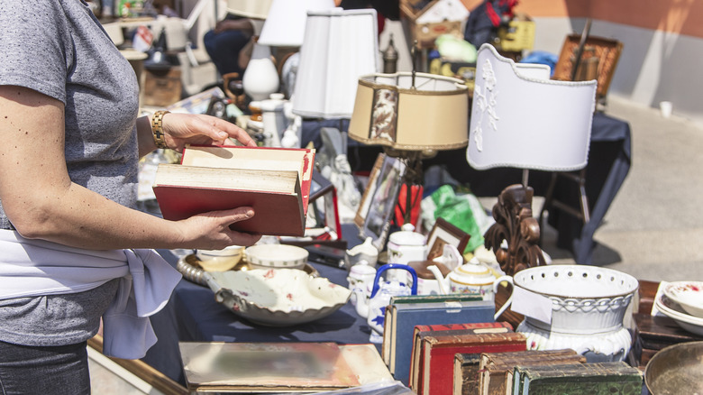 Woman in a grey shirt browses through an outdoor antique shop or flea market