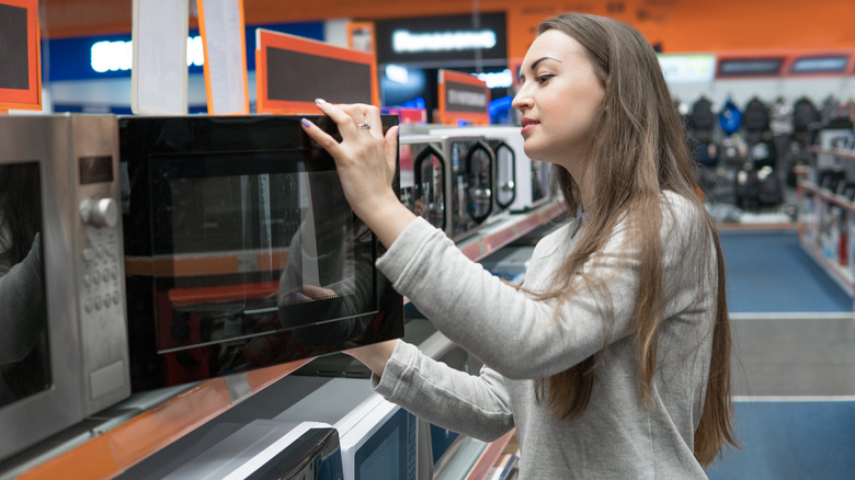 woman shopping for microwave in store