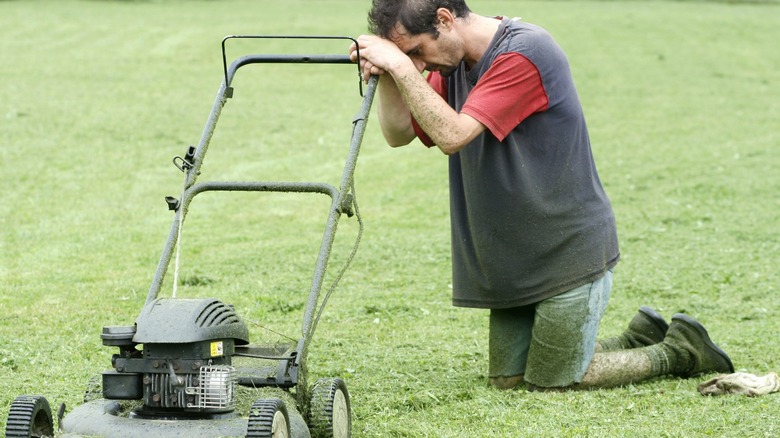 Man with push mower exhausted 