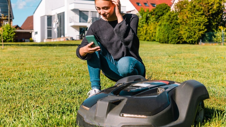 Woman figuring out robotic lawnmower 
