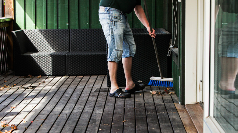 Man sweeping wooden porch