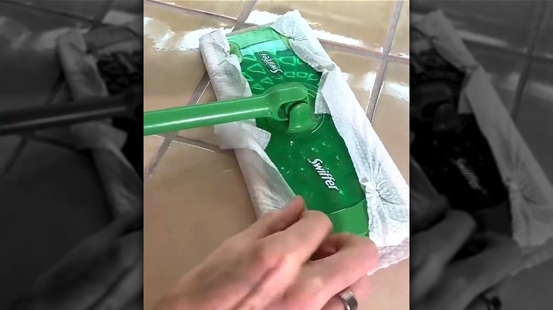 Hand attaching wipes to Swiffer mop