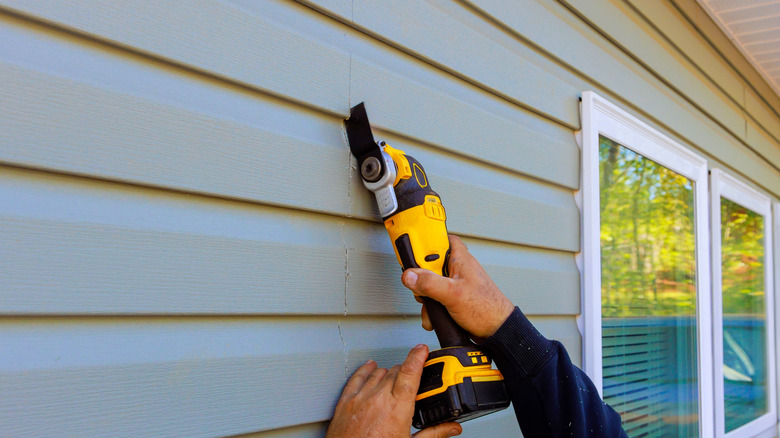 Expert installing vinyl siding to the back of a house