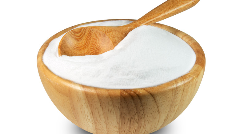 baking soda in wooden bowl with wooden spoon on white background