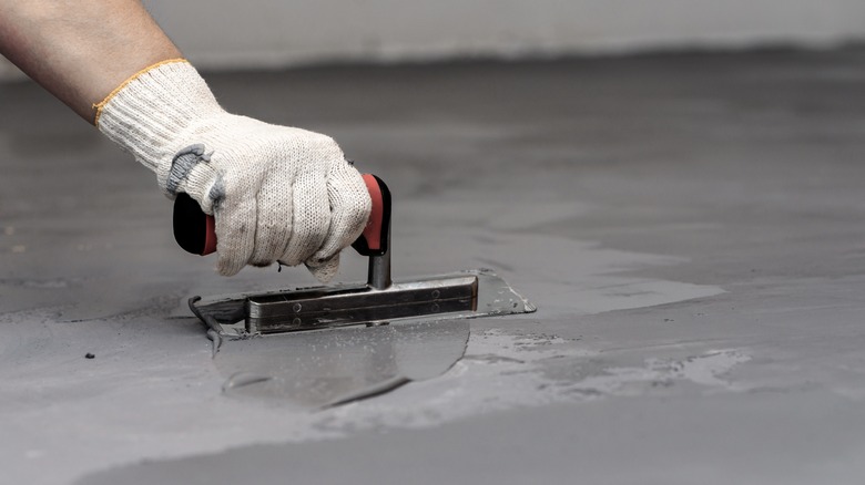 Hand applying cement flooring