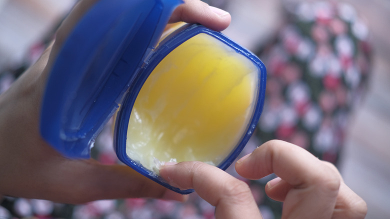 a woman scooping out a little petroleum jelly from the jar