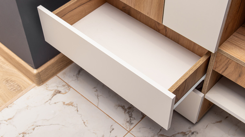 An empty open drawer is in a marble effect room