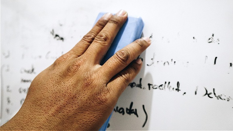 Hand wiping ink off whiteboard 