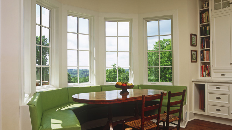 bay windows above green couch and dining table