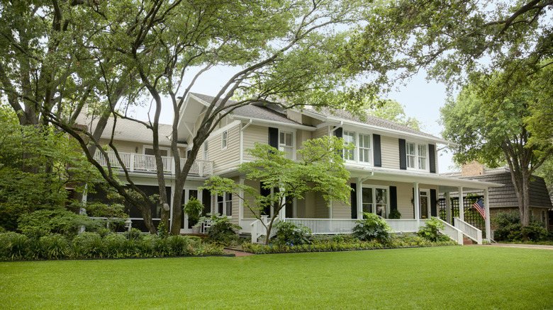 The front yard of a home with trees, shrubs and a large expanse of lawn.