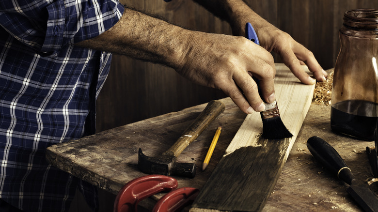 Person staining a wood plank