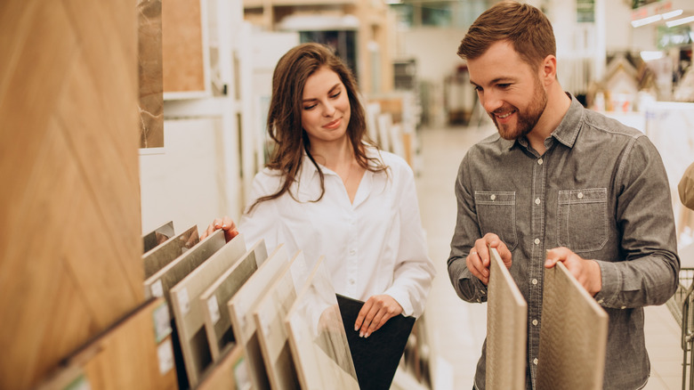 Couple in department store searching through tile choice for their kitchen wall design